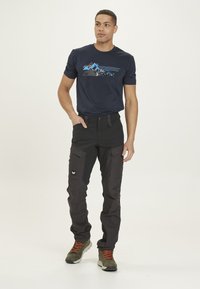 Marintröja med kort ärm och berggrafik; svarta cargo-byxor med flera fickor; grå och orange vandringskängor.