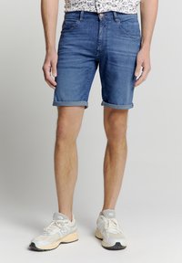 Lichtblauwe denim shorts met opgerolde zomen en een klassiek vijf-pocket ontwerp. G gedragen met lichtgekleurde hardloopschoenen en een gestreept shirt.