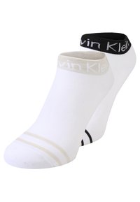 Two pairs of ankle socks: one in white with a beige stripe, another in white with a black stripe. Elasticized cuffs with logo accents.
