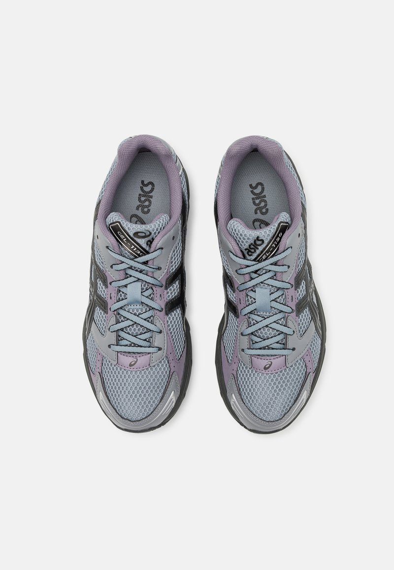 Sportschoenen in grijs en lavendel met een mesh bovenzijde, zwarte accenten, rechthoekige veters en een ronde neus. Heeft een logo op de tong.