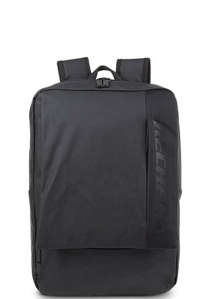 Mochila negra con una textura suave, que cuenta con correas de hombro acolchadas, un bolsillo frontal y el logotipo "SKECHERS" en el lateral.