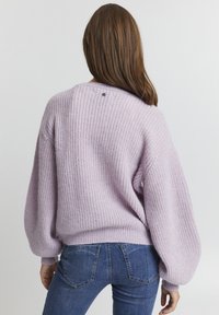 Lavendel gestrickter Pullover mit lockerer Passform, breiten Ballonärmeln und ribbeliger Textur. Verfügt über ein kleines Logo-Detail auf der Rückseite.