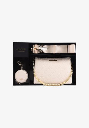 Cream-colored handbag with embossed patterns, gold chain strap, and a matching round keychain in a gift set with a beige shoulder strap.