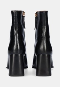 Botines negros de cuero suave. Cuentan con un tacón grueso y una cremallera lateral con lengüeta para ponerlos y quitarlos fácilmente.
