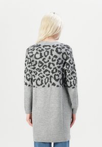 Lungo maglione grigio in morbido knit, con un motivo leopardato nero sulla parte superiore della schiena. Include polsini e orlo a coste.