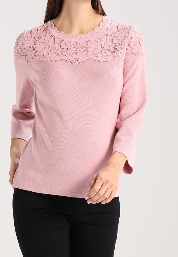 Pull en tricot rose à manches trois quarts, avec un empiècement en dentelle sur la partie supérieure, col rond et texture côtelée.
