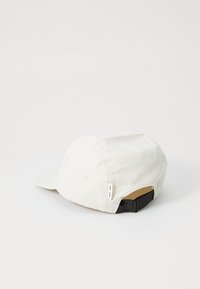White cotton cap featuring a curved brim, adjustable black strap at the back, and subtle stitching details. Smooth texture and rounded shape.