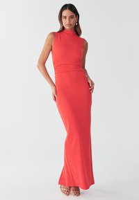 Rød, ærmeløs maxikjole med krappehalsudskæring, tætsiddende overdel og blødt, elastisk stof. Har en slå-ud kant og et minimalistisk design.