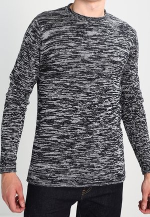 Långärmad stickad skjorta i svart och vitt melerat mönster, med rundad halsringning och ribbade manschetter, tillverkad av mjukt, texturerat tyg.