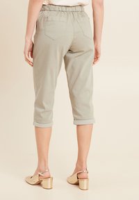 Pantalons courts vert clair avec ourlets retroussés, dotés d'une taille élastique et de deux poches arrière. Associés à des chaussures à talons blocs dorées.