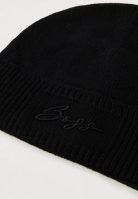 Μαύρο πλεκτό σκουφάκι με ριμπ μανσέτα και κεντημένο λογότυπο σε ταυτόχρωμη μαύρη κλωστή στο μπροστινό μέρος.