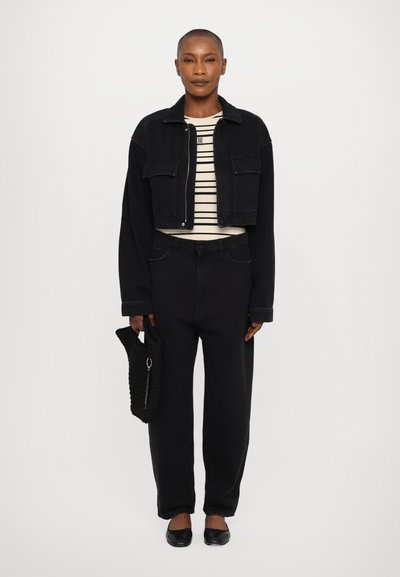 Chaqueta de mezclilla negra corta con dos bolsillos delanteros sobre una camiseta de rayas. Pantalones de pierna ancha de alta cintura en negro y un bolso texturizado negro.