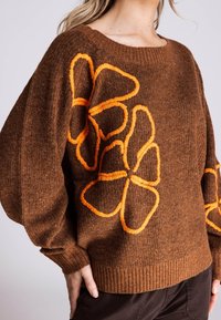 Brauner gestrickter Pullover mit übergroßen Ärmeln und einem gerippten Saum, verziert mit orangefarbenen Blumendetails. Weiche Textur und entspannte Passform.