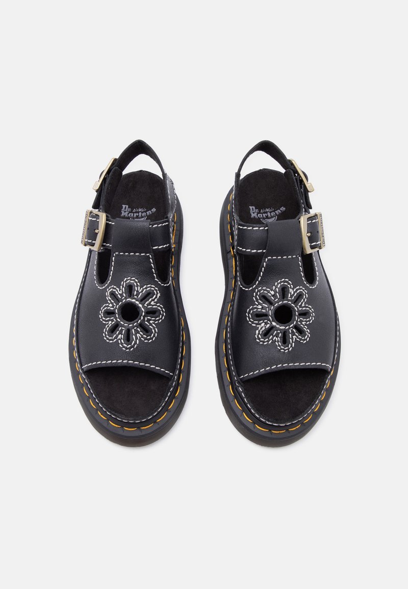 Sandali neri in pelle con punte aperte, cinturini alla caviglia con fibbie, cuciture bianche e ritagli a forma di fiore sulla tomaia.