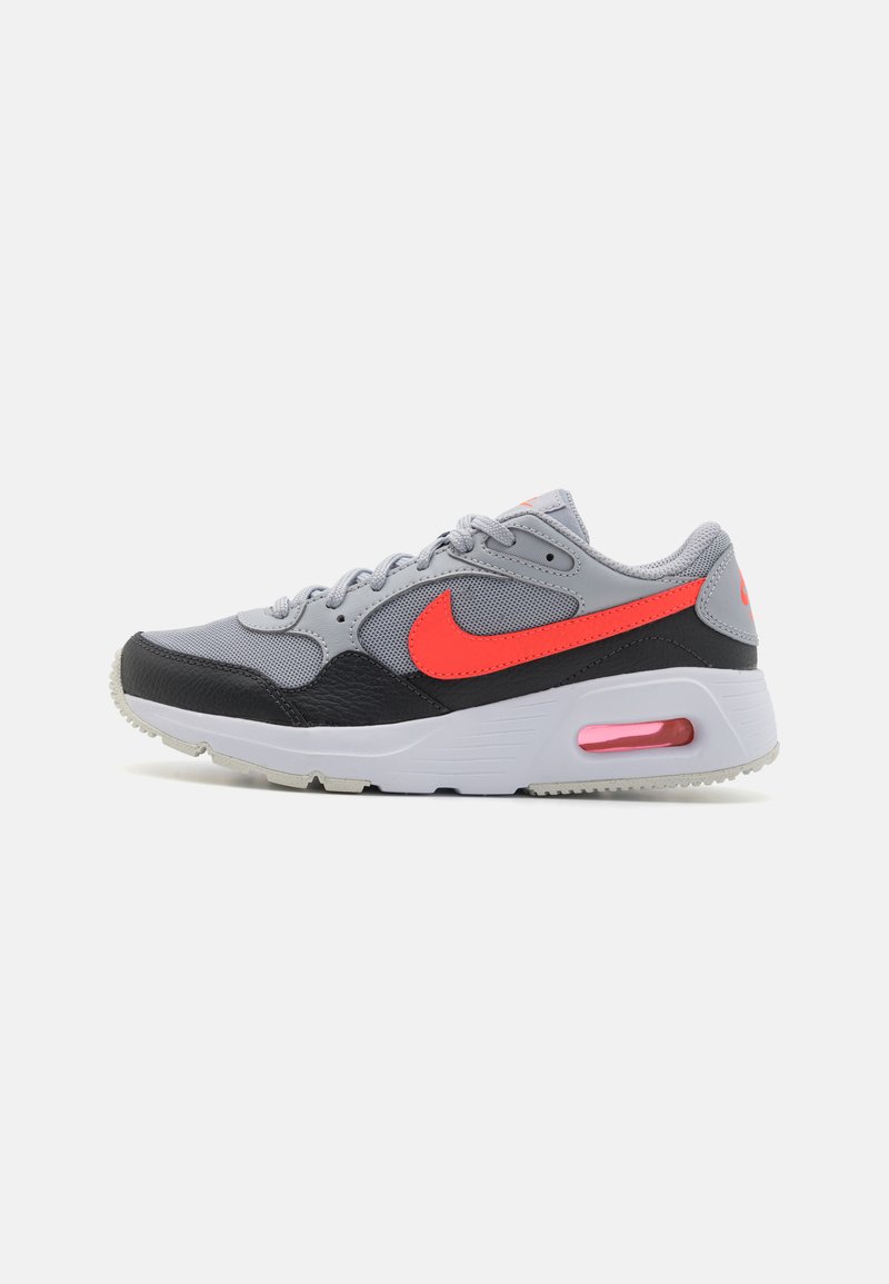Baskets grises avec des accents noirs, logo Nike rouge, tissu texturé et amorti air visible. Conçues avec des lacets et une semelle extérieure en caoutchouc.