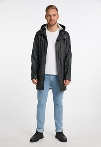 Sort vandtæt jakke med hætte, lynlås lukning, flere lommer og en glat tekstur. Båret over en hvid t-shirt og blå jeans.