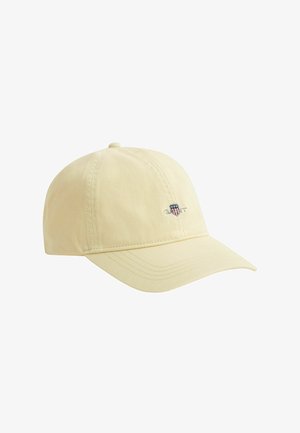 Cappellino da baseball giallo chiaro con visiera curva e piccolo logo ricamato che presenta uno scudo con stelle e strisce sul pannello frontale.