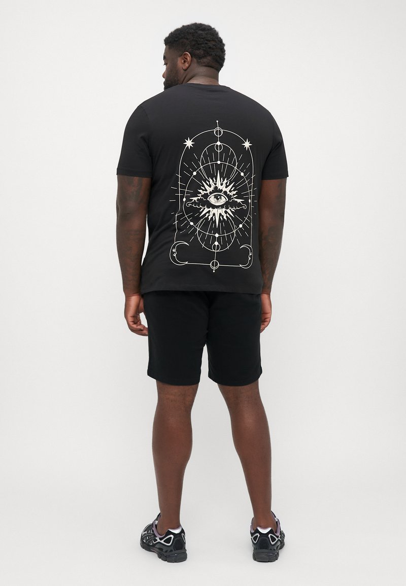 Black t-shirt featuring a white eye design on the back, short sleeves, and a round neckline, paired with black shorts and sneakers.