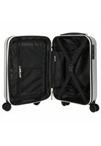 Hartschalentrolley in Hellgrau mit einem Logomuster. Besitzt ein schwarzes Innenfutter, eine Netz-Reißverschlusstasche, Kreuzgurte und leichtgängige Rollen.