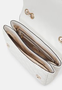 Balta siuvinėta rankinė su auksinėmis detalėmis, turinti dvi compartments, išklotas smėlio spalvos medžiaga su logotipo detalėmis ir užtrauktuku uždaromą kišenę viduje.