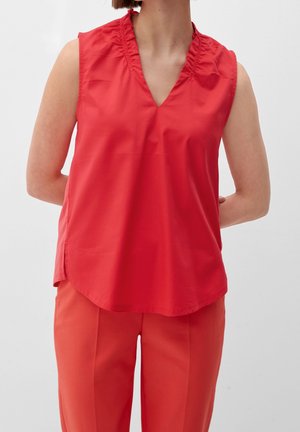 Rote ärmellose Bluse mit V-Ausschnitt und Rüschenausschnitt, aus glattem Stoff; kombiniert mit passenden roten Hosen.