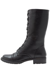 Bota de cuero negro hasta la rodilla con punta redonda, sistema de cordones en la parte delantera y tacón plano. Textura suave con detalles de costura en los laterales.