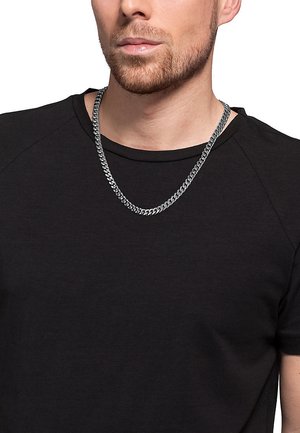 Silverfärgad kedja med tjocka, sammanlänkade länkar, bärs över en svart T-shirt. Kedjan har en polerad yta som reflekterar ljus.