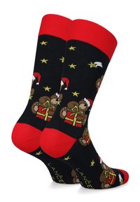 Czarne skarpetki z czerwonymi mankietami, przedstawiające misia w czapce Mikołaja, trzymającego prezent, ozdobione żółtymi gwiazdkami i białymi akcentami.