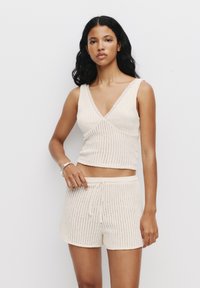 Crème ribgebreide lounge set met een mouwloos topje met een V-hals en bijpassende shorts met een trekkoord en een geschulpte zoom.