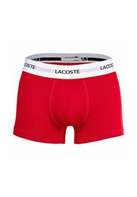Červené bavlnené boxerky s bielym pásom s čiernym logom "LACOSTE" a tvarovaným vreckom na podporu.