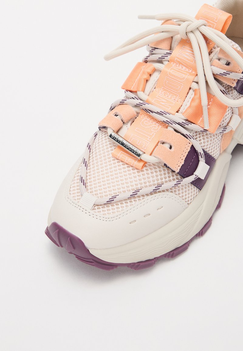 Scarpa sportiva con tomaia in mesh di un leggero pesca e crema, caratterizzata da accenti viola, lacci elastici e suola testurizzata per una buona presa.