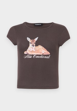 T-shirt à manches courtes brun foncé avec un faon couché portant un nœud rose et le texte « Miss Emotional » en écriture cursive sous l'animal.
