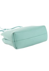 Sac à main en cuir bleu clair doux avec une fine bandoulière, montré en contre-plongée mettant l'accent sur la base et les coutures latérales.