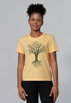 T-shirt en coton jaune avec un design d'arbre vert comprenant des branches et des racines. Manches courtes et col rond. Texture plate.