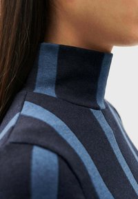 Marine gestreepte coltrui met afwisselende donkerblauwe en lichtblauwe banden; slim-fit ontwerp met een textuurafwerking en hoge kraag.