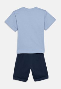 Ανοιχτό μπλε βαμβακερό μπλουζάκι με κοντά μανίκια και στρογγυλή λαιμόκοψη, συνδυασμένο με σκούρο μπλε βαμβακερό σορτς, και τα δύο με απαλή υφή.