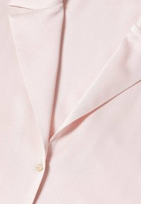 Camicia in satin rosa chiaro con colletto a risvolto, chiusura a bottoni e texture liscia con dettagli di cucitura precisi.
