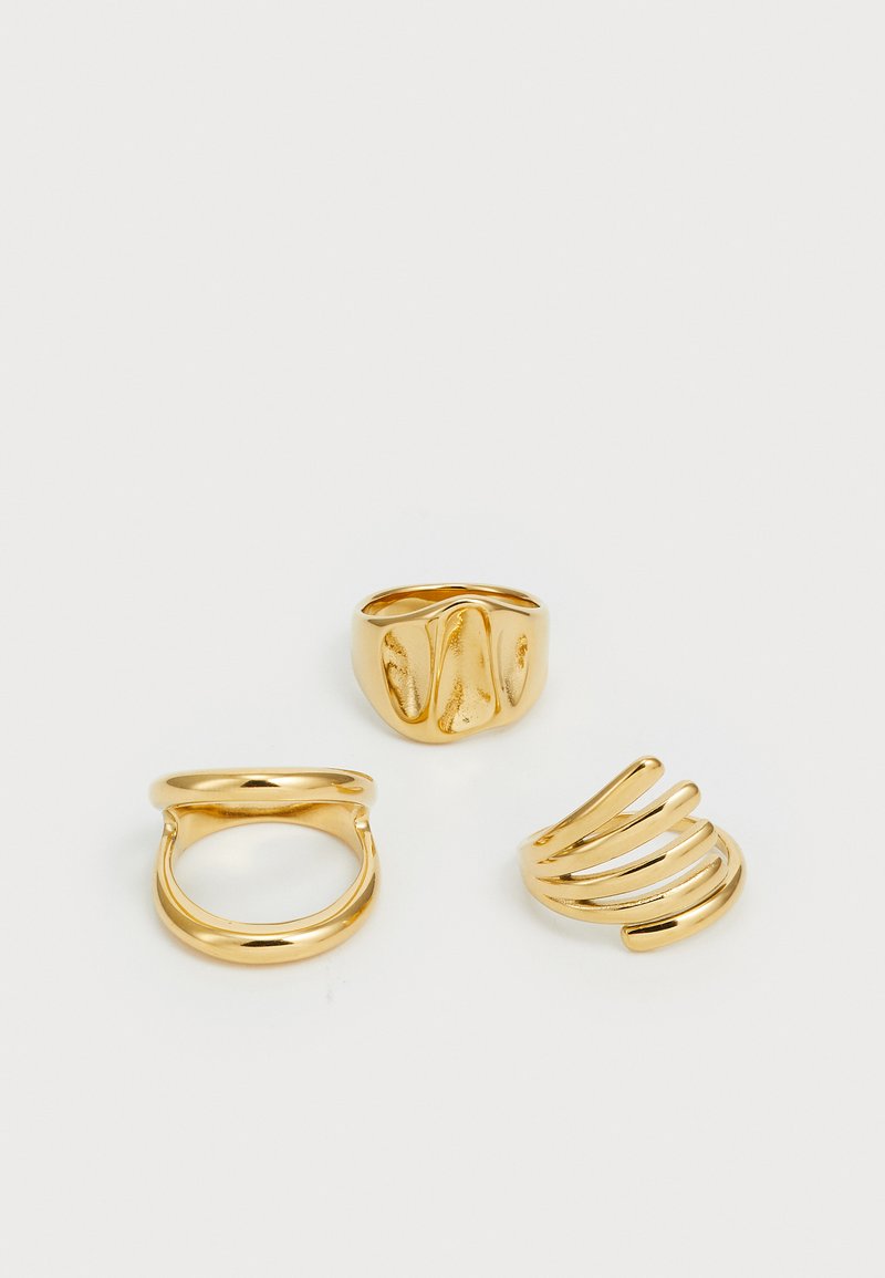 Tre gullringer: en glatt ring, en vridd design med teksturert overflate, og en spiralring med buede linjer.