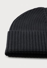 Svart ribbestrikket beanie-hatt med brettet oppkant, vist liggende flatt på hvit bakgrunn.