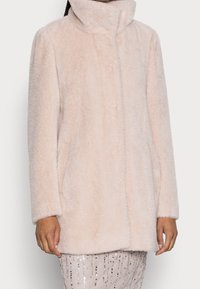 Abrigo de pelo sintético en rosa claro, con un alto cuello, mangas largas y bolsillos laterales. Textura suave con un diseño minimalista.
