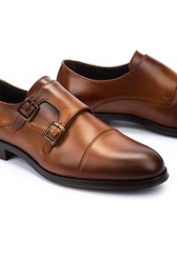 Zapatos de cuero marrón con una textura suave, acentos de doble hebilla, un punta redonda formal y un tacón bajo y plano.