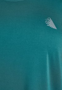 Tyrkysové elastické tričko s okrúhlym výstrihom a bielym grafickým dizajnom, ktorý obsahuje horizontálne pruhy na jednej strane.