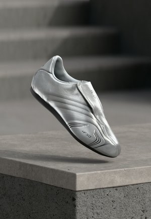 Silver soccer shoe with sleek, smooth leather, a streamlined shape, featuring subtle texture lines and a black rubber sole. Notable +F50 branding.