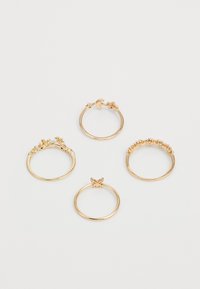 Cuatro anillos de oro con diseños variados: uno con acentos florales, uno liso, uno adornado y uno con un detalle de una sola gema.