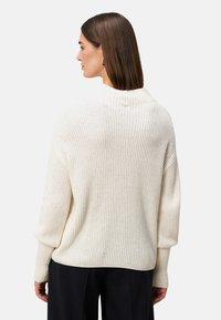 Crème-kleurige, oversized gebreide trui met ribbelstructuur en een hoge halslijn, voorzien van verlaagde schouders en een losse pasvorm.
