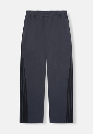 Marineblauwe sportbroek met een elastische tailleband, zijzakken en verticale zwarte strepen aan de zijkanten. Glad stoftextuur.