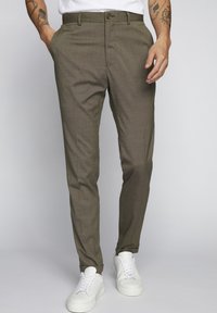 Bruna texturerade byxor med slim fit, som har en knappstängning och sidofickor, matchade med vita sneakers.