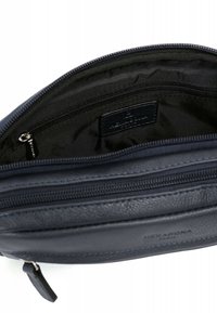 Donkerblauwe leren pouch met een gladde textuur, voorzien van een ritssluiting en een zwarte stoffen binnenkant, waarin een klein ritsvak zichtbaar is.