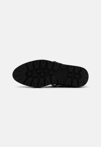 Semelle de chaussure en caoutchouc noir avec un motif de grip texturé, dotée de rainures profondes et d'un design à bout arrondi. Les accents comprennent un léger détail en rainure.