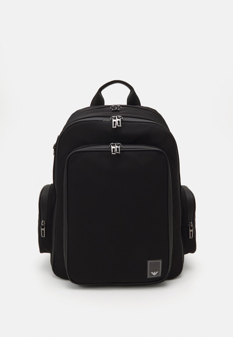 Mochila negra con múltiples compartimentos con cremallera, un respaldo acolchado y bolsillos laterales. Hecha de un tejido duradero con una textura suave.